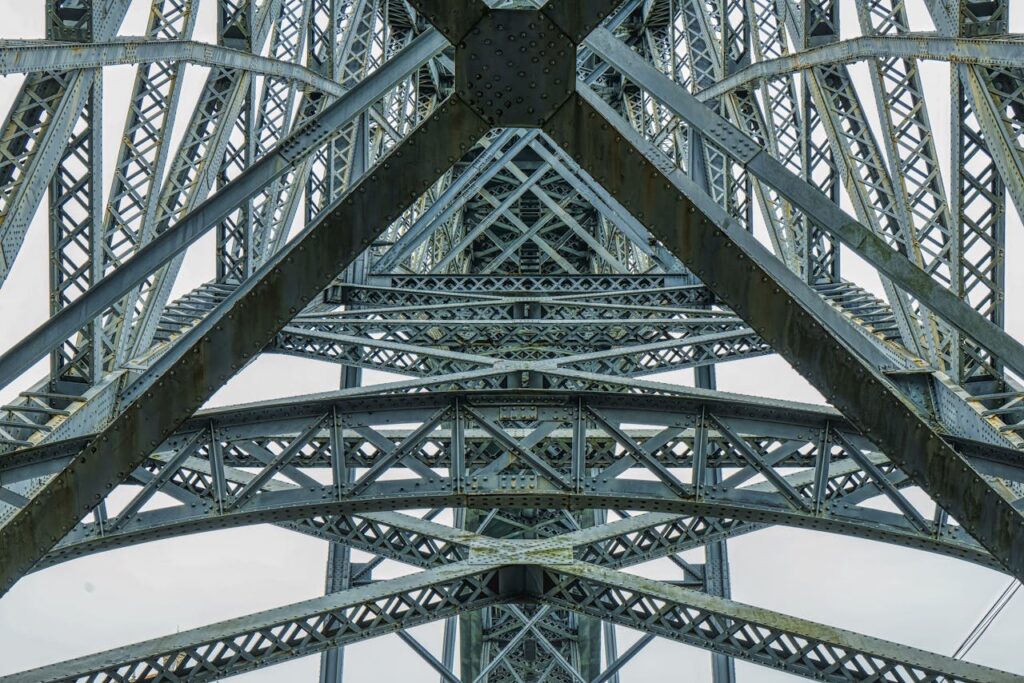 Low angle view of an intricate steel structure with a focus on frameworks and rivets.
